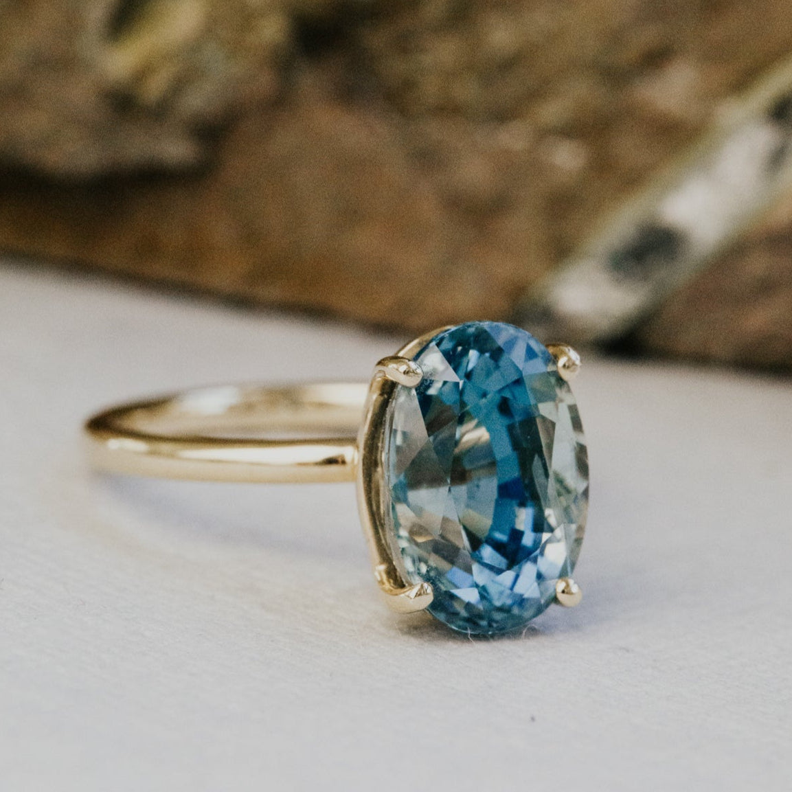 Gold ring with a blue sapphire gemstone on a wooden surface