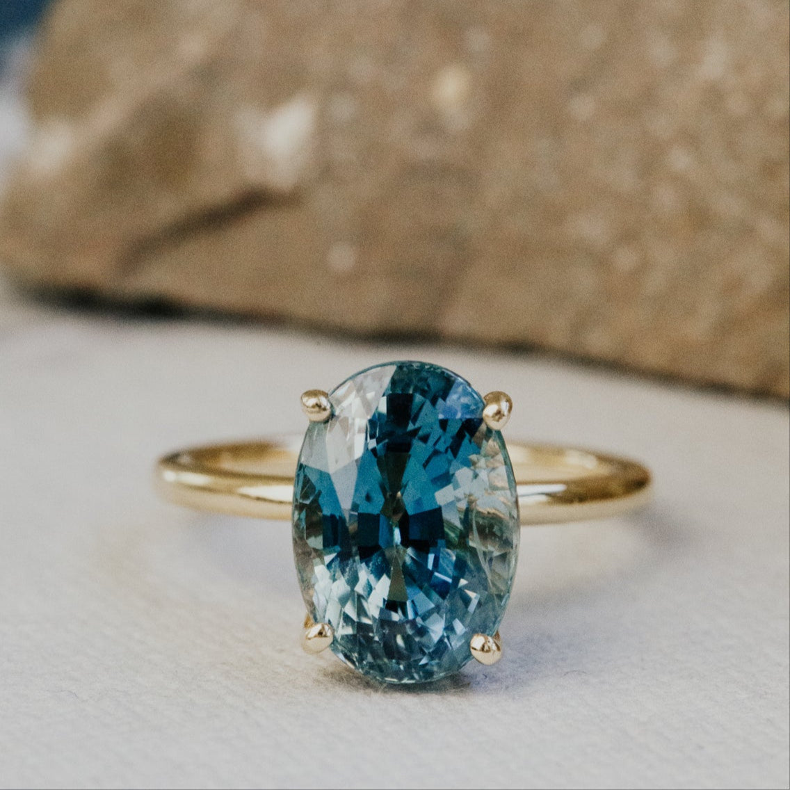 Gold ring with a blue gemstone on a textured surface