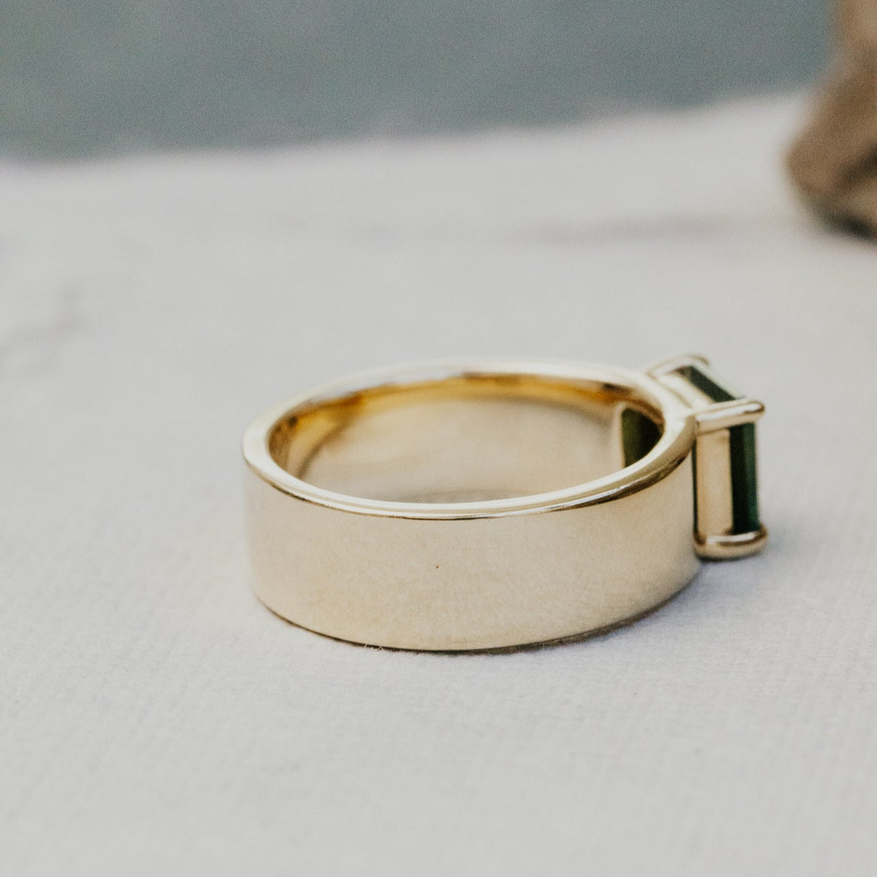 Gold ring on a light gray surface with a blurred background