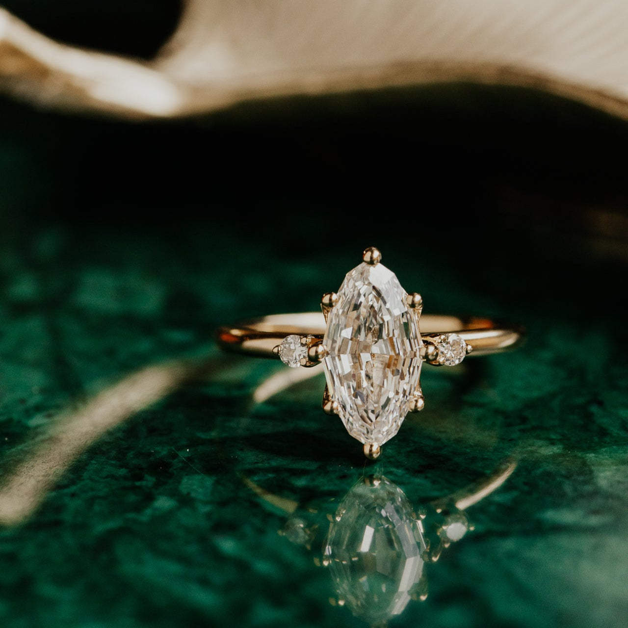 Gold ring with a marquise lab grown diamond on a green surface