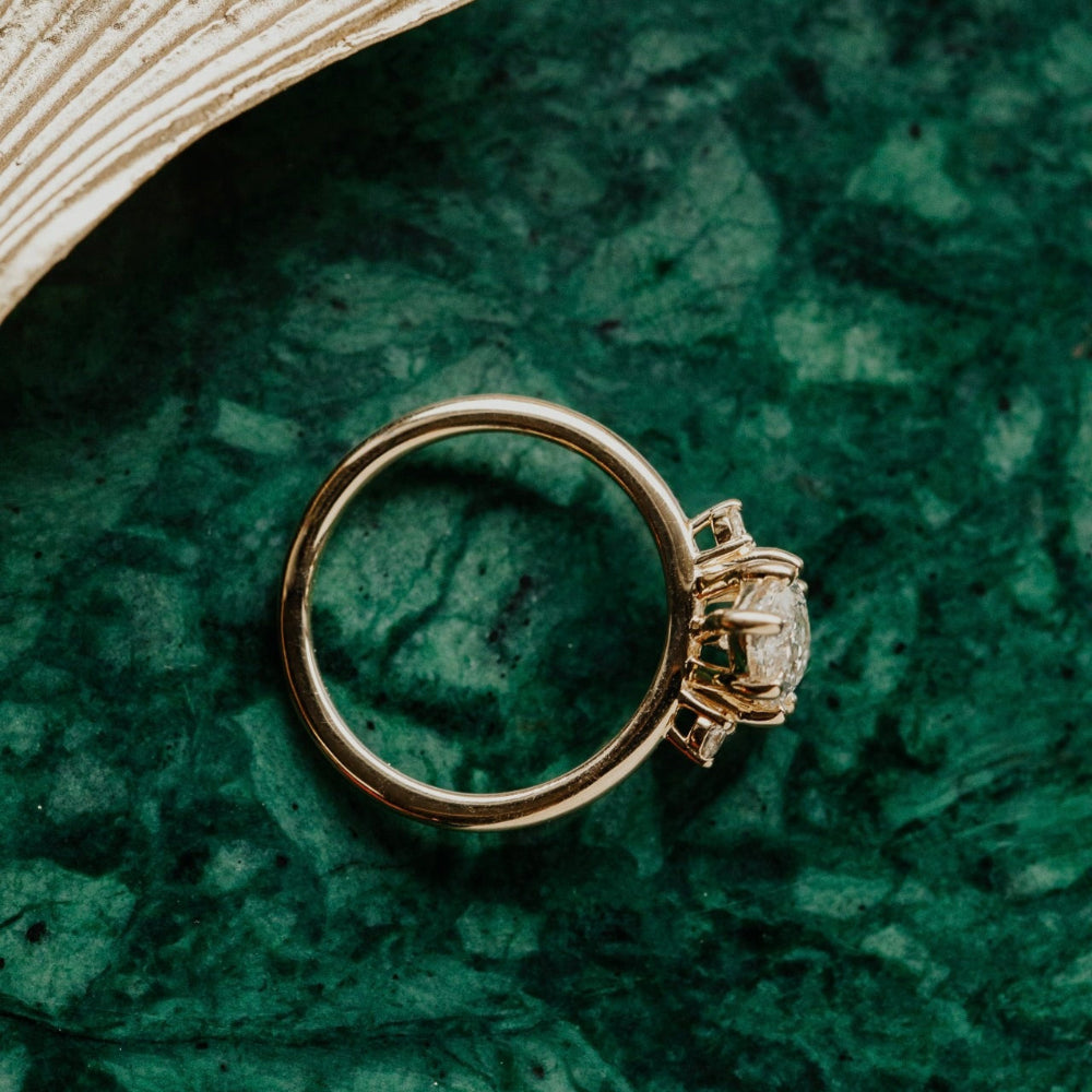 Gold ring with a marquise  lab grown  diamond on a green textured surface