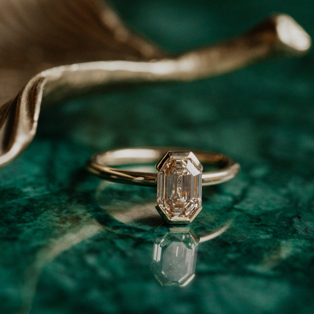 Gold ring with a diamond on a green textured surface