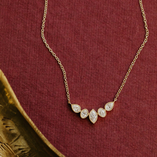 Gold necklace with diamond pendants on a red fabric background