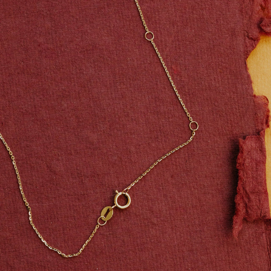 Gold chain necklace on a textured red fabric background