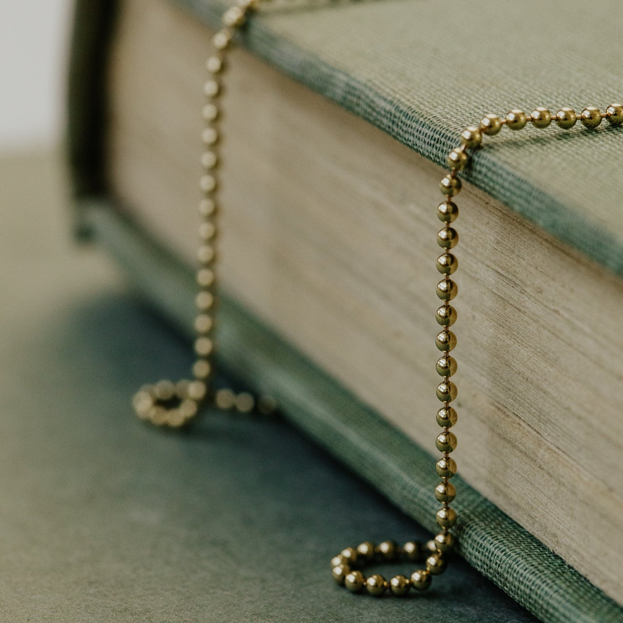 Gold necklace draped over an open book on a textured surface