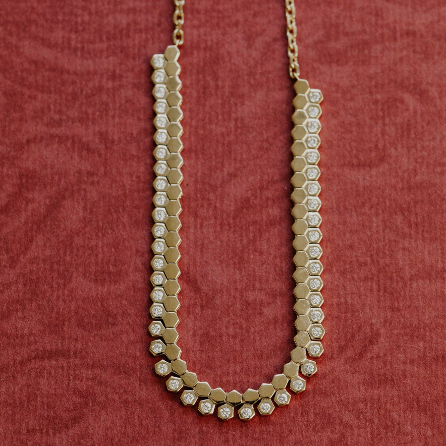 Gold necklace with hexagonal beads on a red textured background