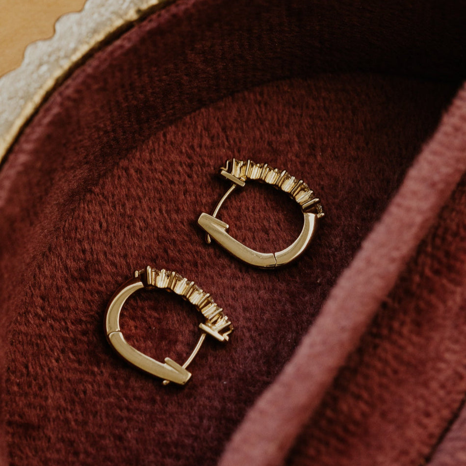 Gold hoop earrings on a textured red surface
