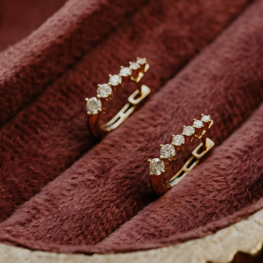 Gold earrings with diamond stones on a textured brown surface