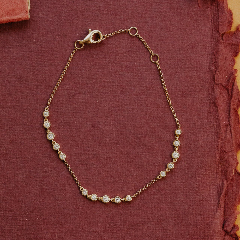 Gold bracelet with diamond beads on a textured red fabric background