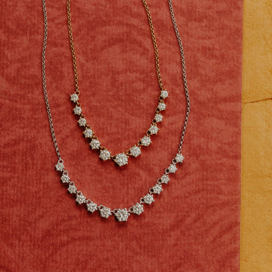 Two diamond necklaces on a red fabric background