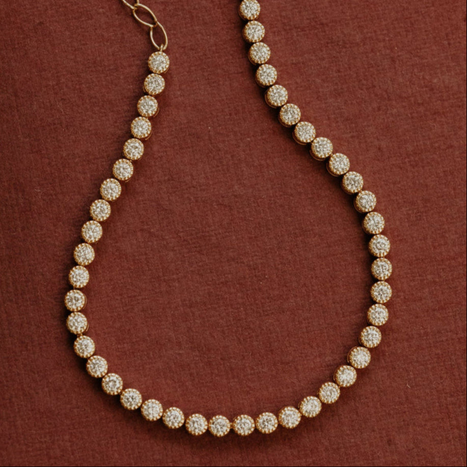 Gold diamond tennis bracelet on a brown textured background