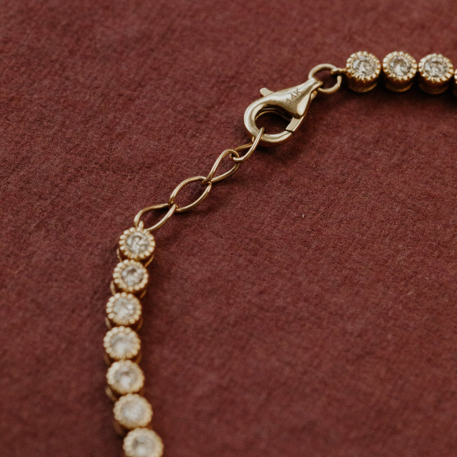 Gold bracelet with diamond-like beads on a red background