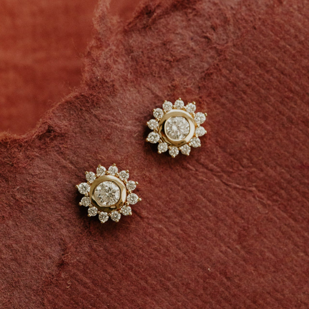Gold and diamond earrings on a textured red surface