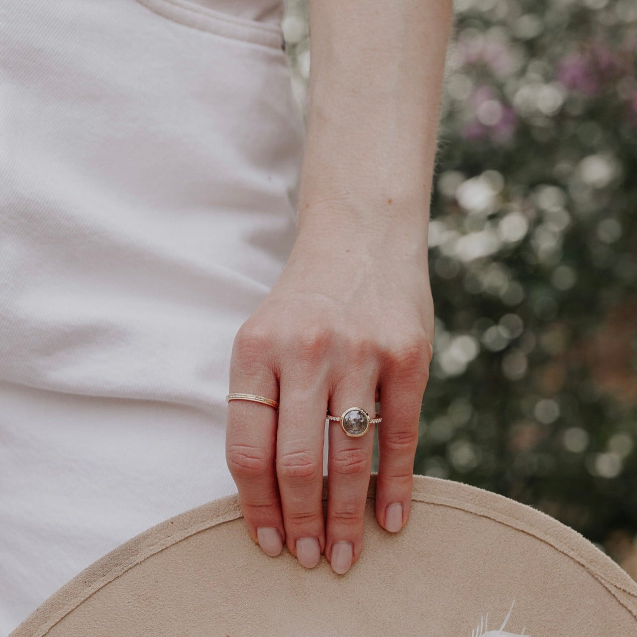 14k gold ring featuring a round grey rustic diamond set in a milgrain bezel with a .09 cttw pave diamond band.