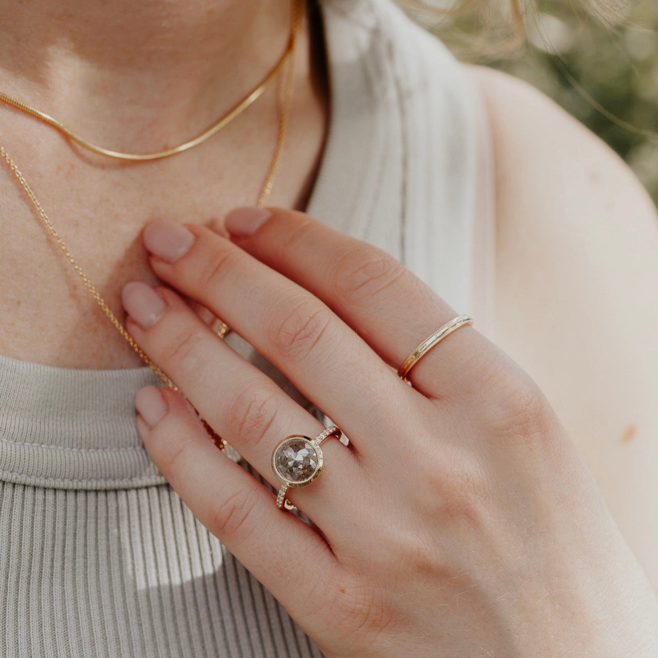 14k gold ring featuring a round grey rustic diamond set in a milgrain bezel with a .09 cttw pave diamond band.
