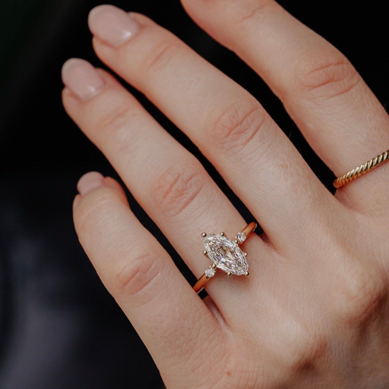 Hand wearing a a marquise  lab grown  diamond ring with a blurred background