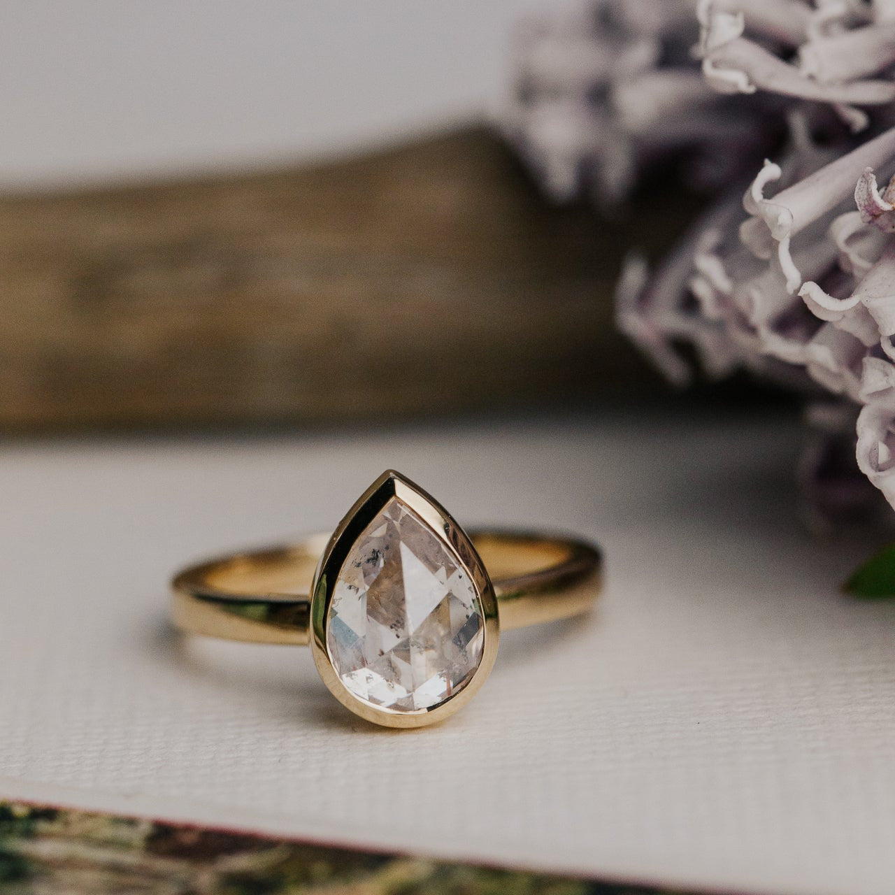 14k gold ring featuring a clear pear rustic rose cut diamond set in a bezel design.