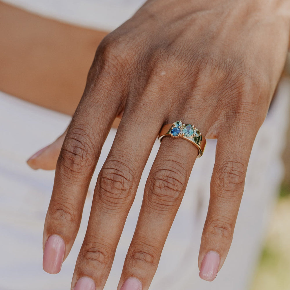 Hand wearing a ring with Australian Sapphire gemstones on a blurred background