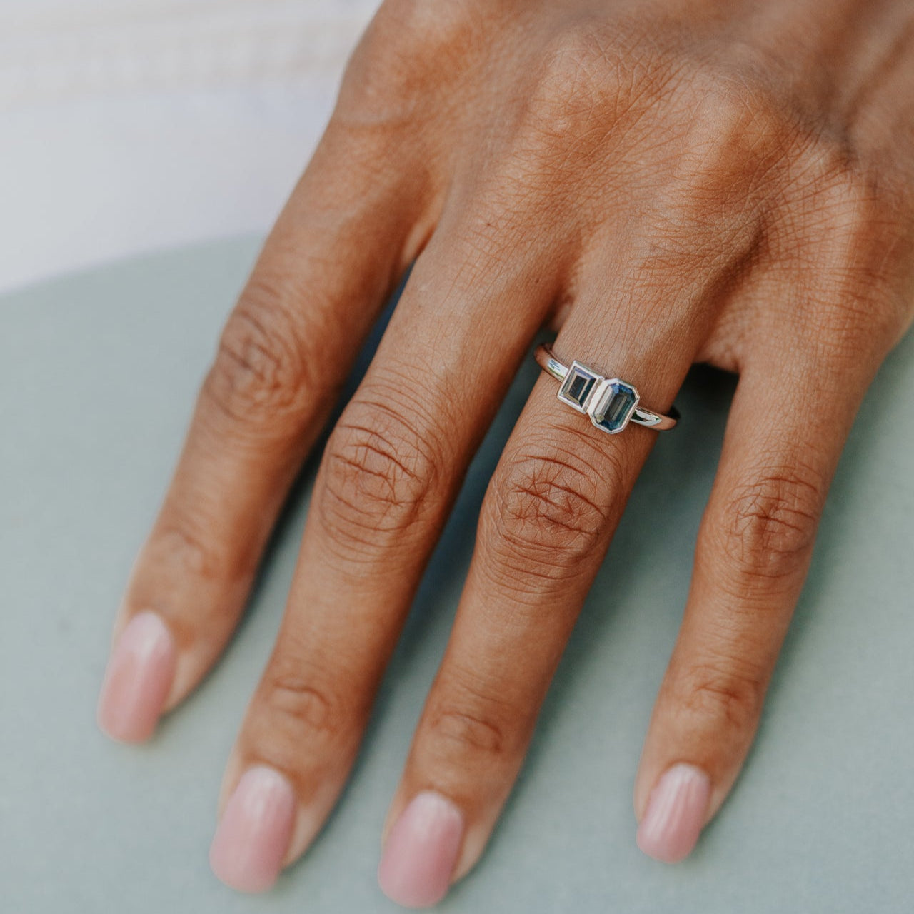 Hand wearing a white gold ring on a light background
