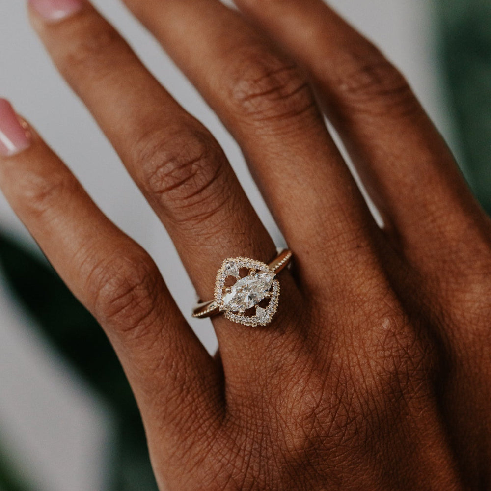 Close-up of a hand wearing a diamond ring with a blurred background