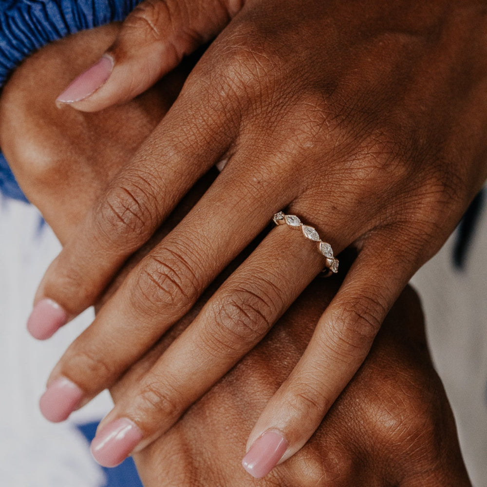 Close-up of hands with a marquise diamond band on a blurred background