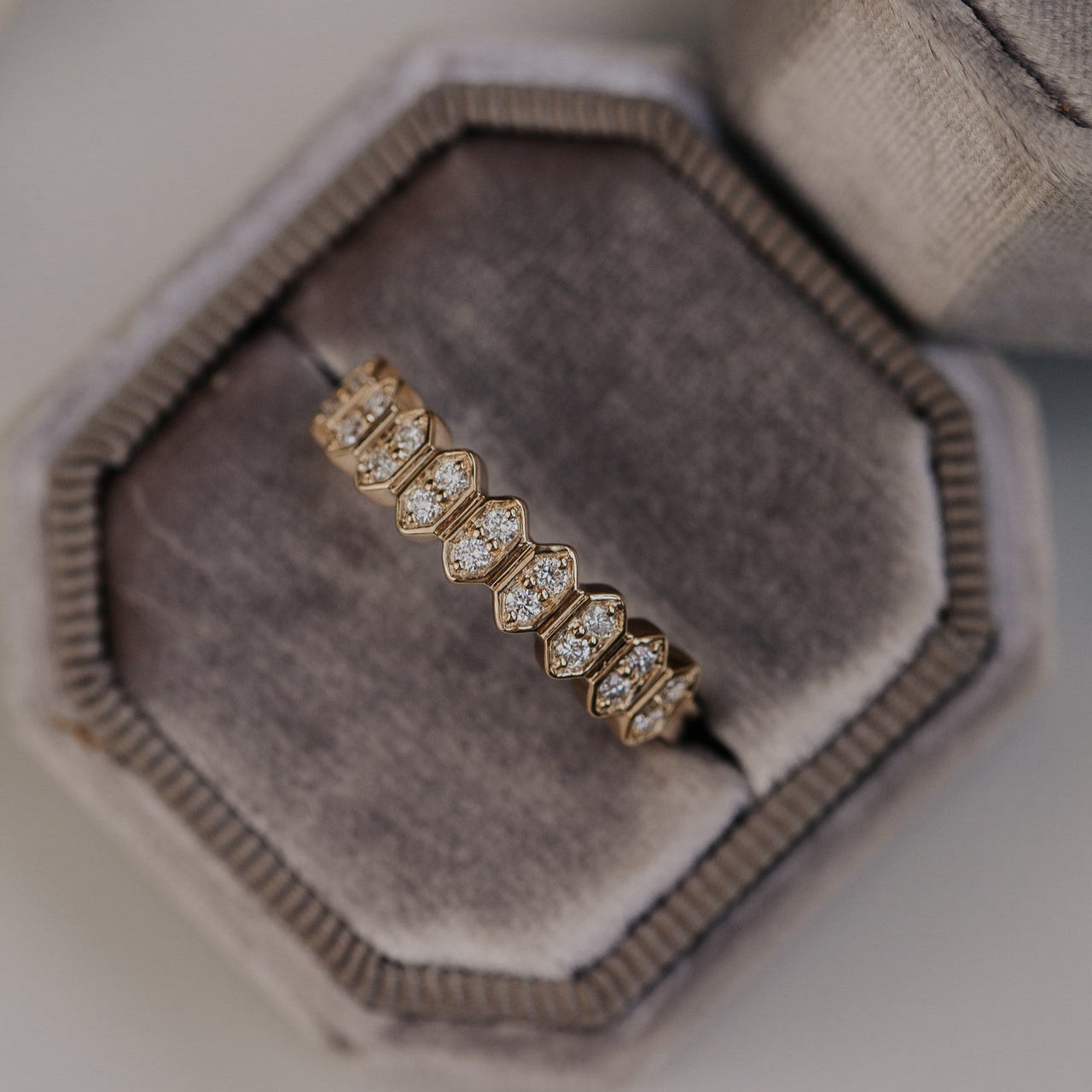 14k gold wedding band featuring round diamonds set in an elongated hexagon pattern.