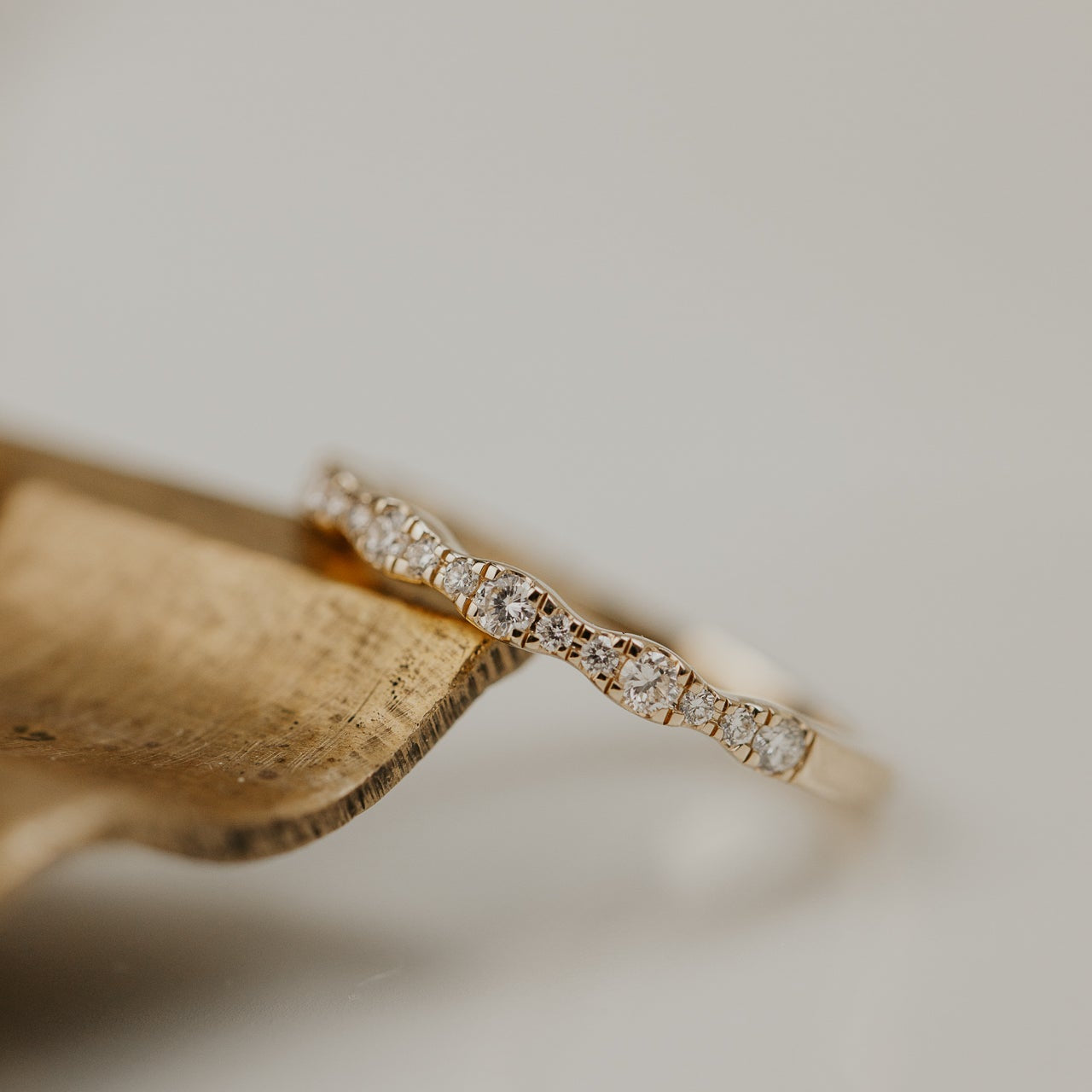 14k gold band  featuring ~.29 cttw pave round diamonds in a wave pattern