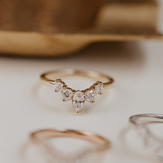 14k gold wedding band with round and oval diamonds, set in prongs in a starburst design.