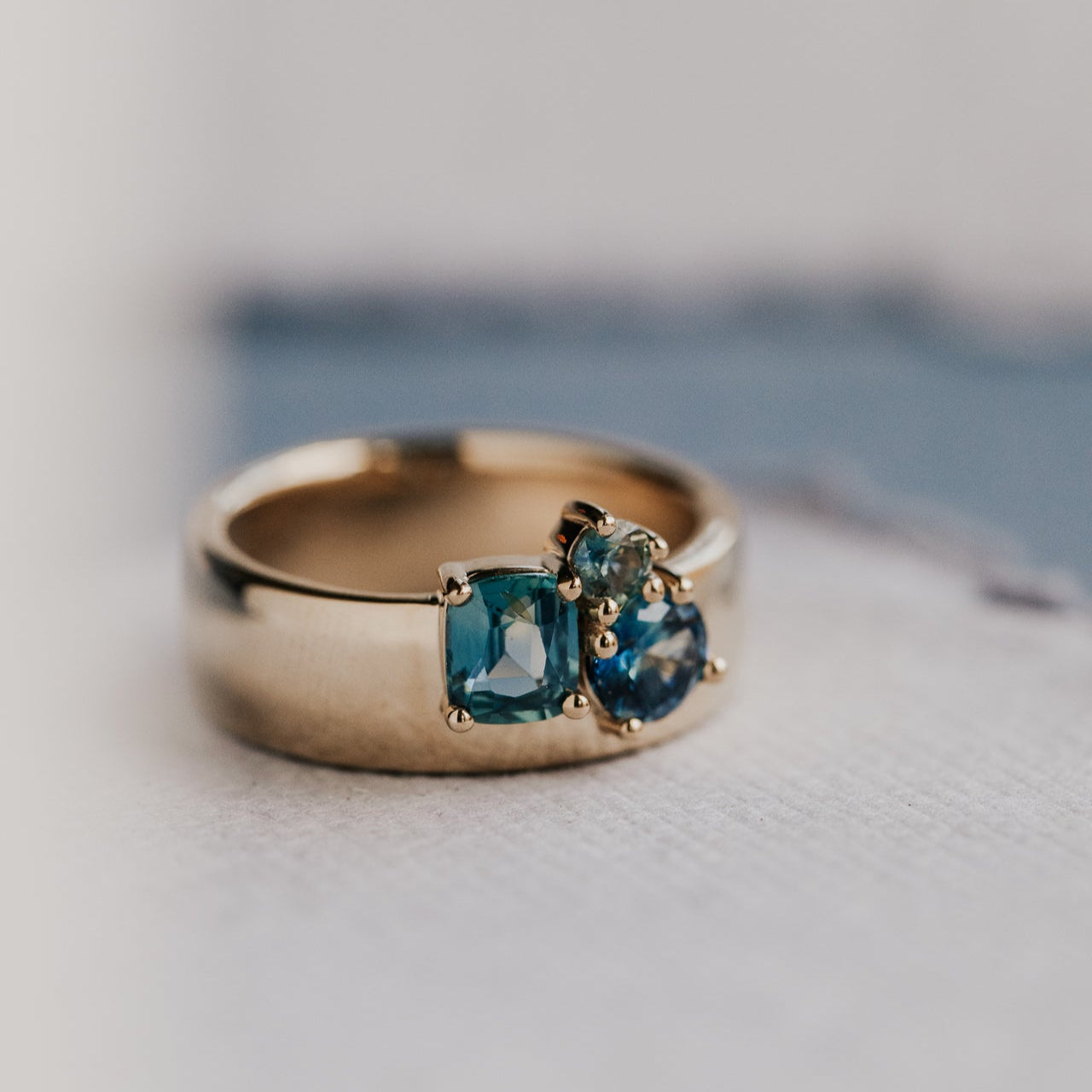 Gold ring with blue sapphires on a light surface