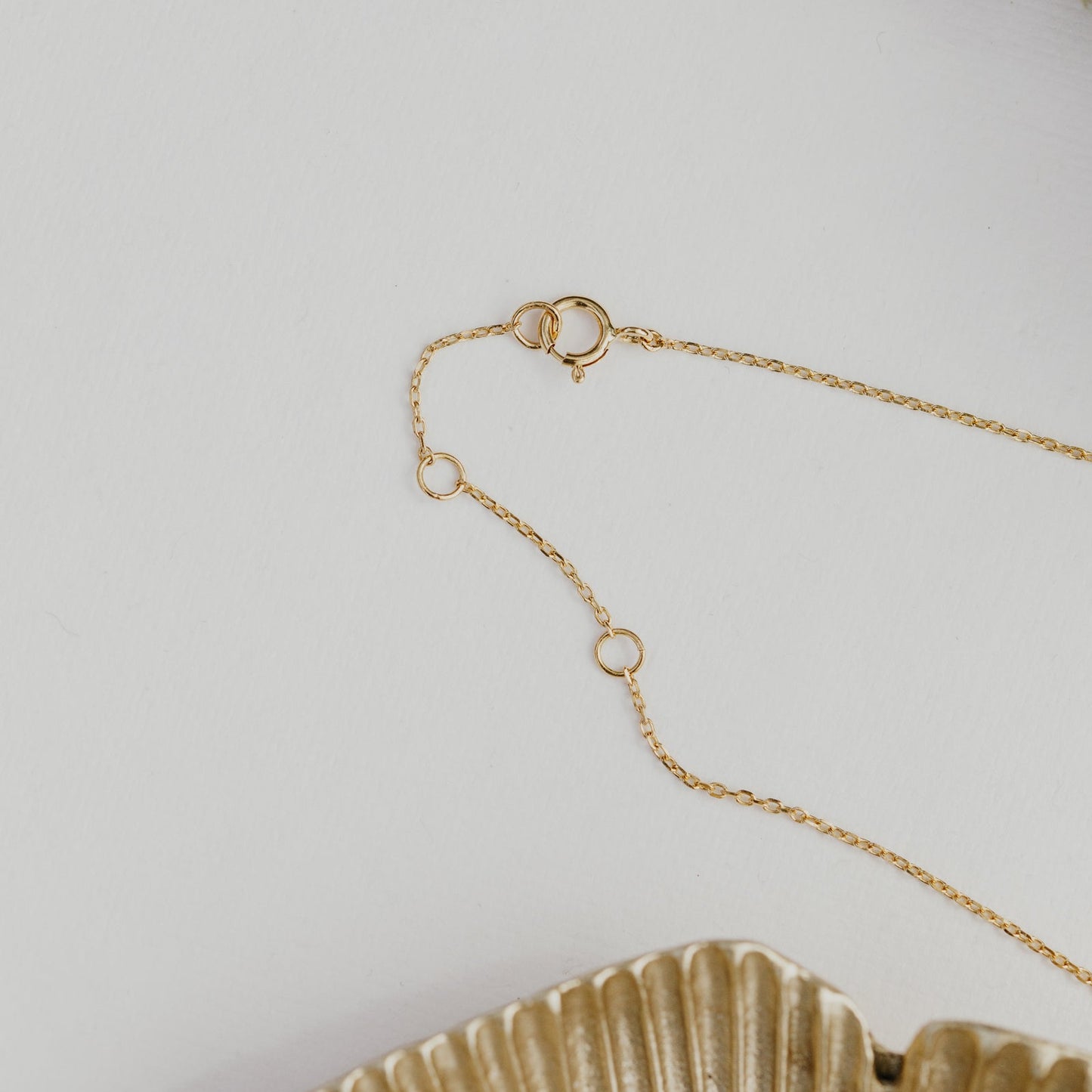 Gold chain necklace on a light gray background.