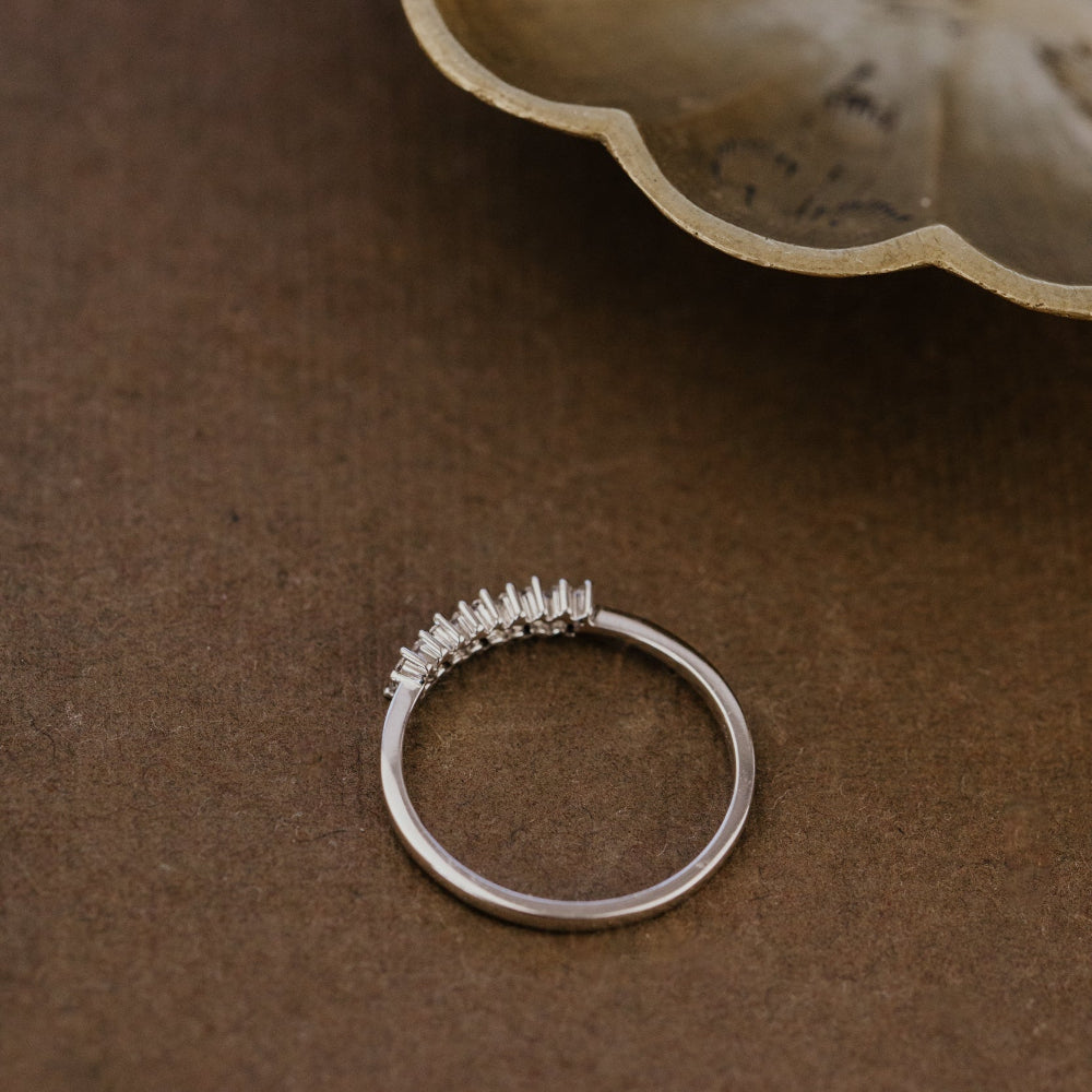 White gold wedding band with diamonds on a brown surface.
