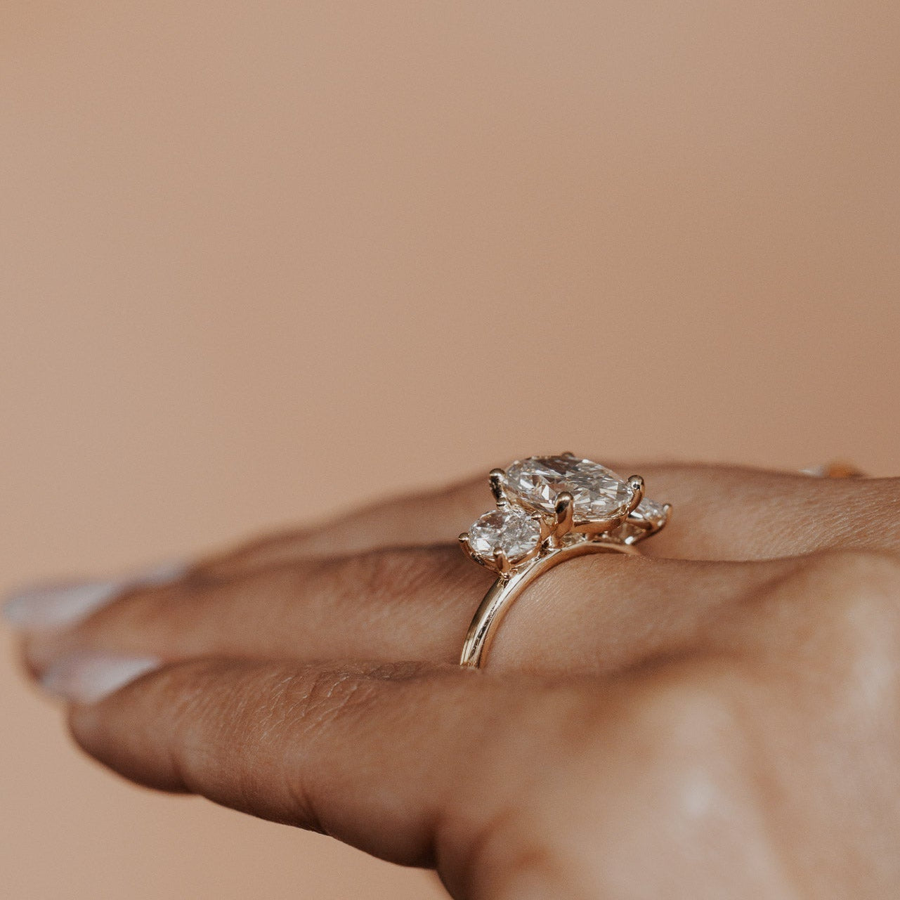 The Hannah Oval Ring in 14k yellow gold worn on the ring finger, shown from a side angle against a warm neutral background.