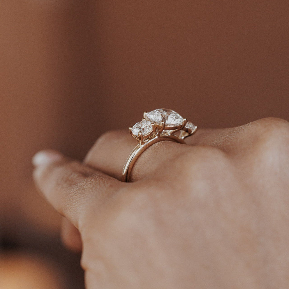 The Hannah Round Ring in 14k yellow gold worn on the ring finger, shown from a side profile angle against a warm neutral background.
