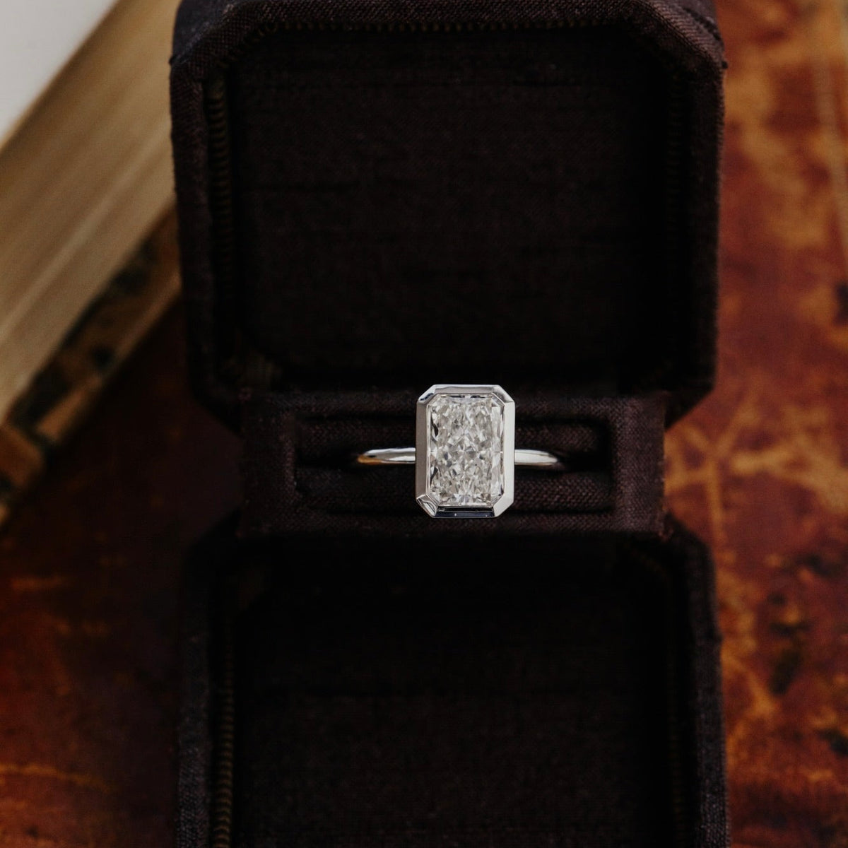 Bailey radiant cut diamond engagement ring in a black velvet box on a textured surface.