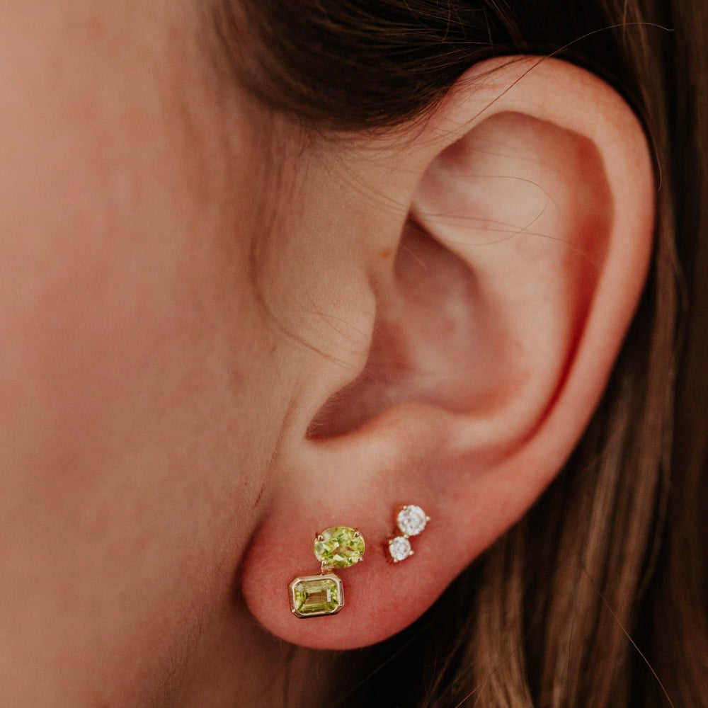 Close-up of an ear wearing three earrings with a warm color tone.
