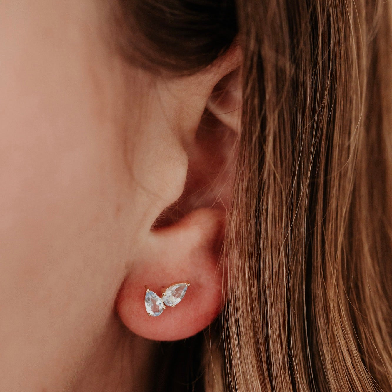 Close-up of an ear wearing a diamond earring with blurred background