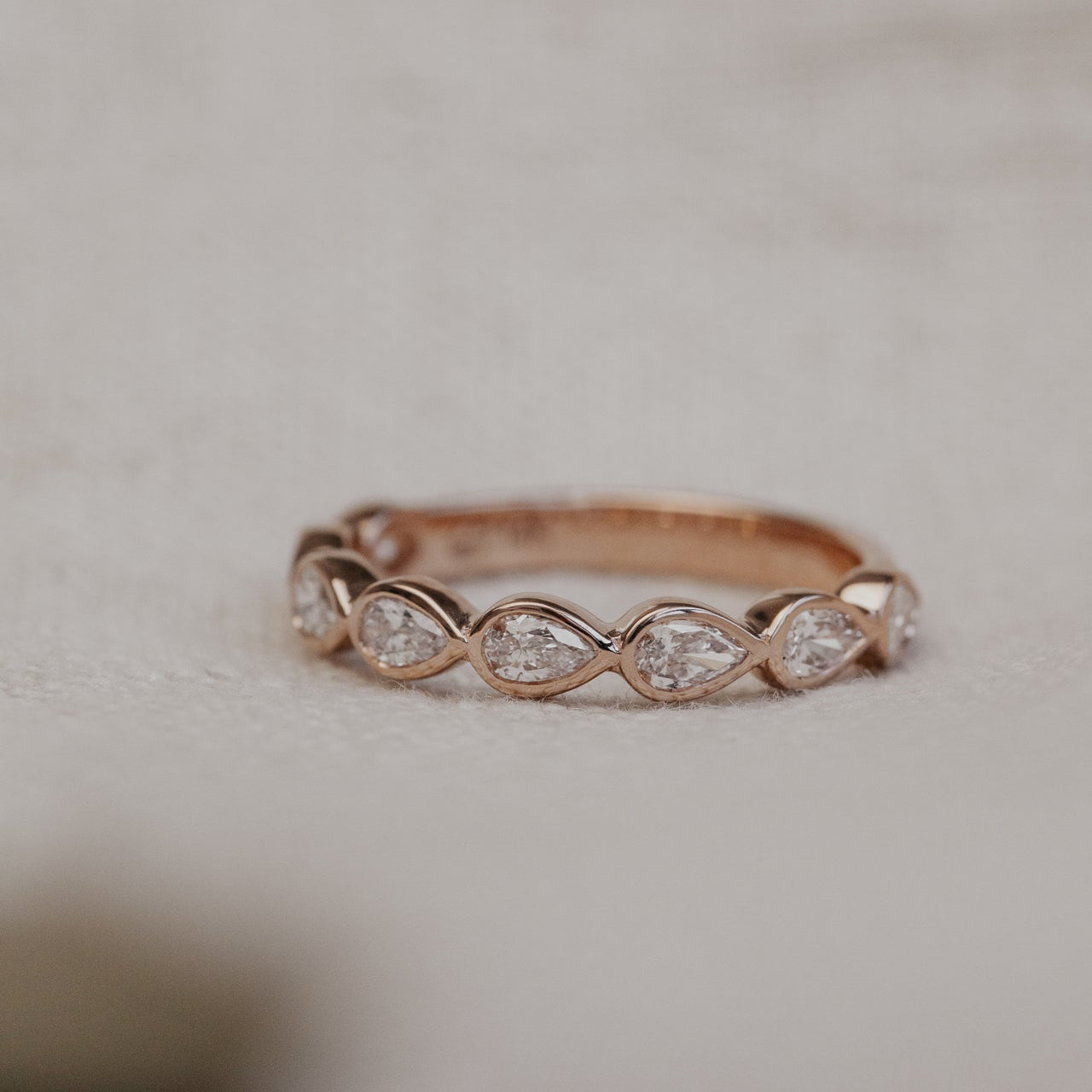 Rose gold ring with diamonds on a light background