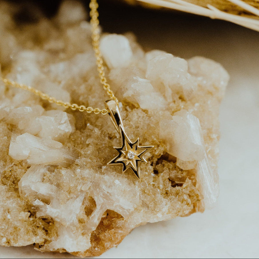 Gold necklace with a star pendant on a textured surface