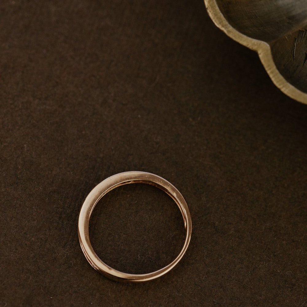 Rose wedding band ring on a brown textured surface.