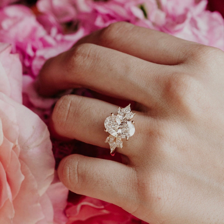 Hand wearing a oval diamond ring on pink flowers