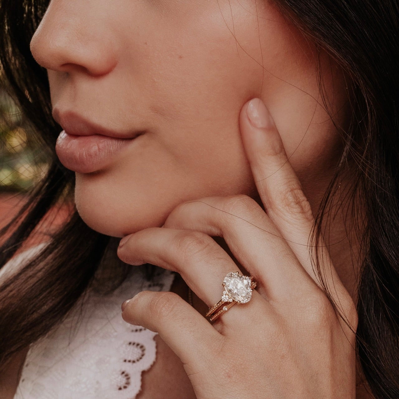 Close-up of a woman wearing a oval diamond ring on her finger.