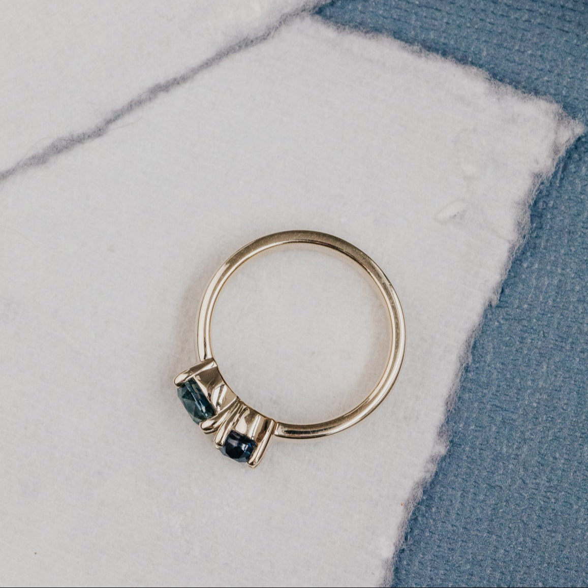 Gold ring with blue Montana sapphire gemstones on a marble surface