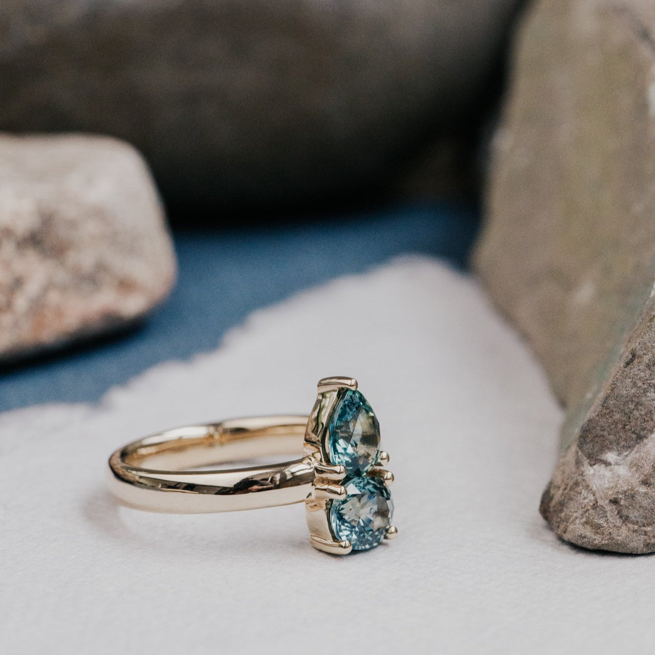 Gold ring with blue Montana sapphire on a stone surface