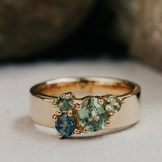 Gold ring with green Australian Sapphire gemstones on a neutral background