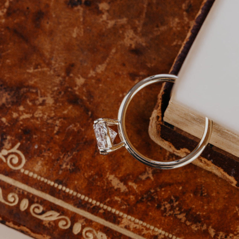 Yellow gold engagement ring with a oval diamond on an ornate brown surface