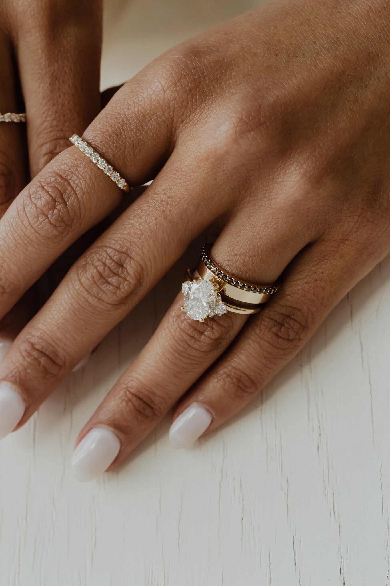The Jenna Black Diamond Band paired with The Vivien Oval Ring and The Thin Gold Stacker on a models hand