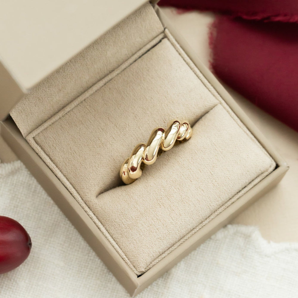 A 14k yellow gold chunky twist ring in a beige setting, presented in a soft-colored box.