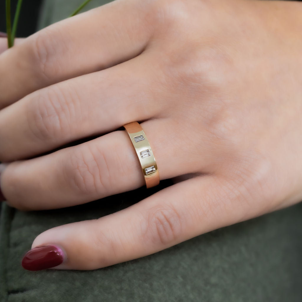The Jaden Three Baguette Wedding Band in 14k yellow gold on a models hand