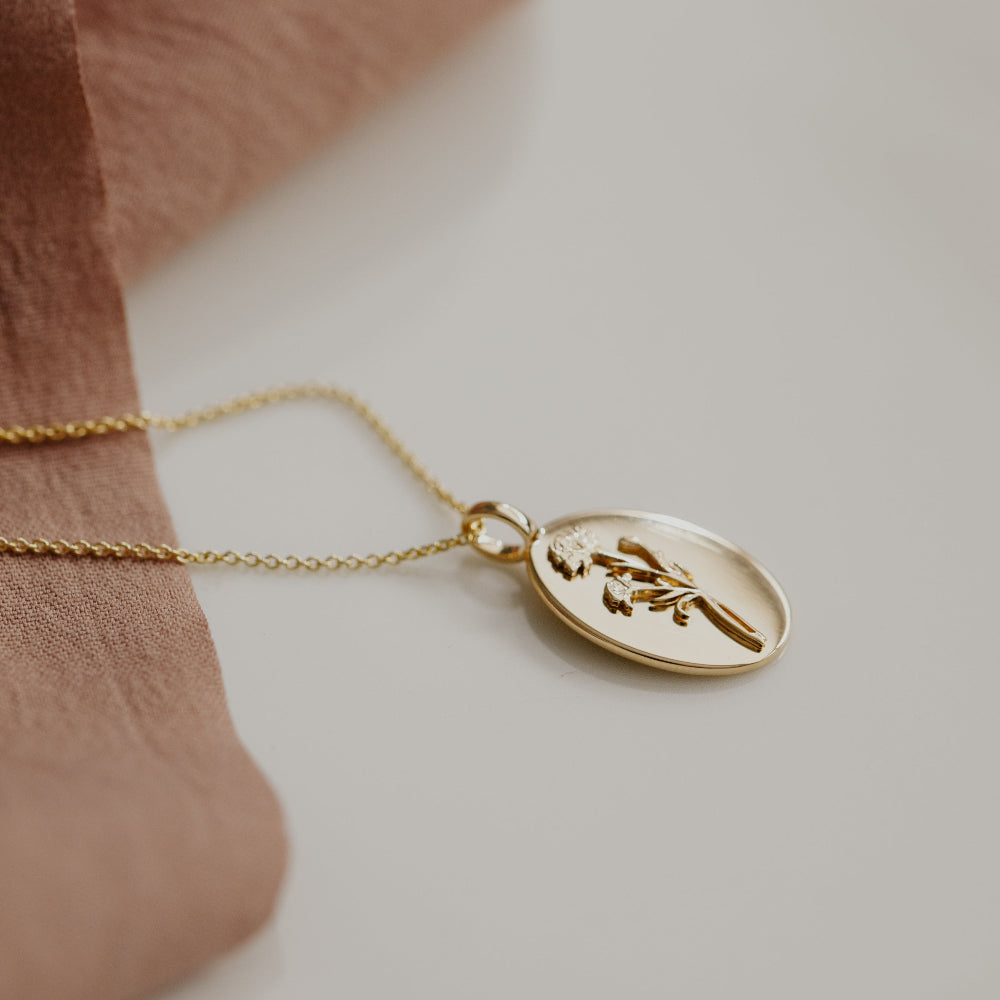 Gold necklace with a pendant on a soft brown fabric background