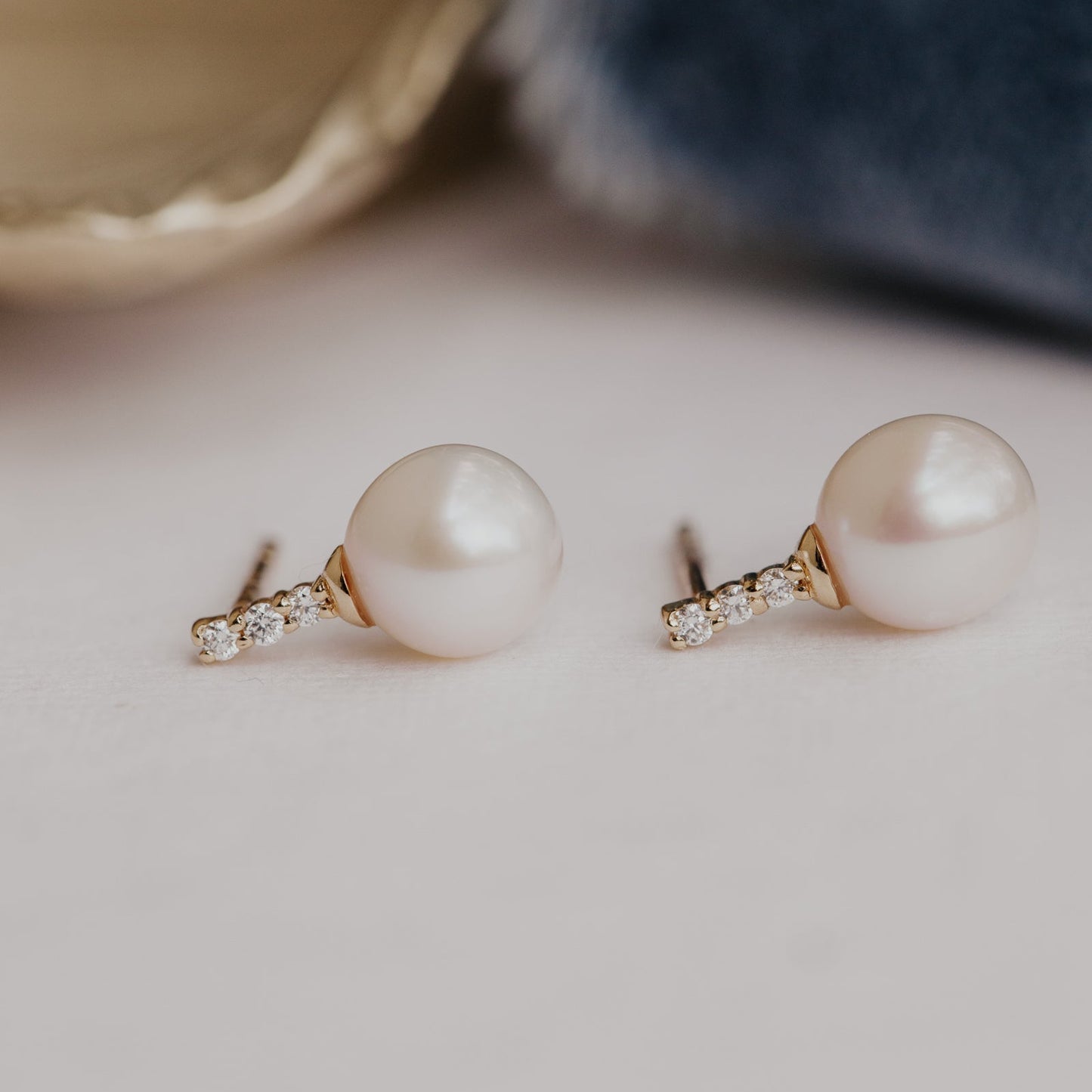 Pearl earrings with gold settings on a neutral background